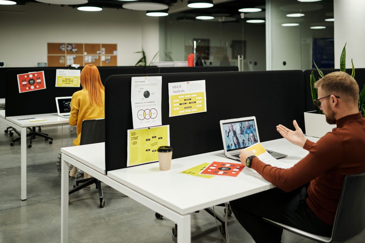 Professional on a video call at an open-plan office desk during a job search